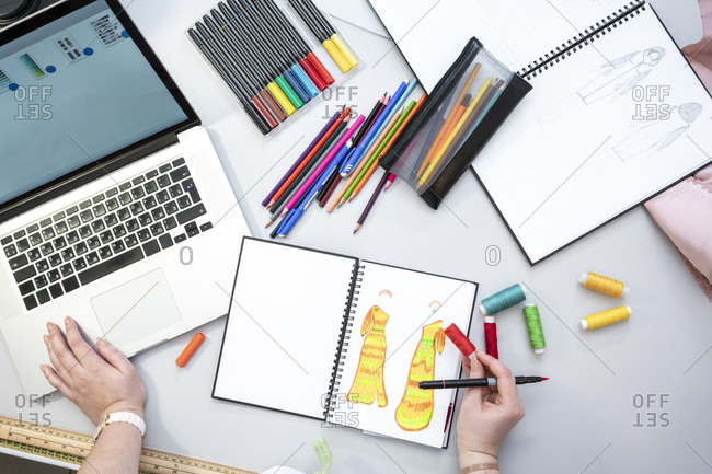 Seamstress using laptop and designing a dress- view from above