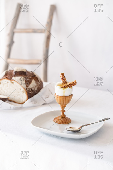 Two crackers with sesame seeds in a broken boiled egg on a wooden stand on a table with a white tablecloth