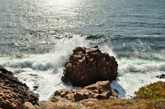 The wave is crashing on the rock near the coastline