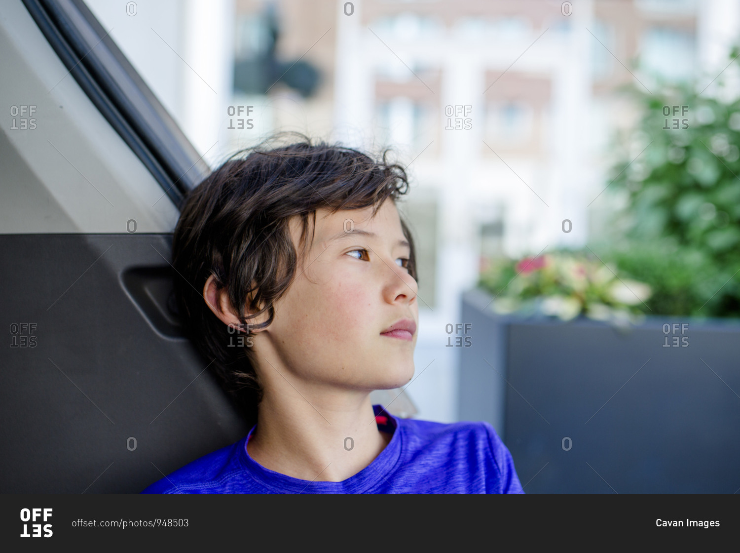A boy traveling on public transportation gazes out the window