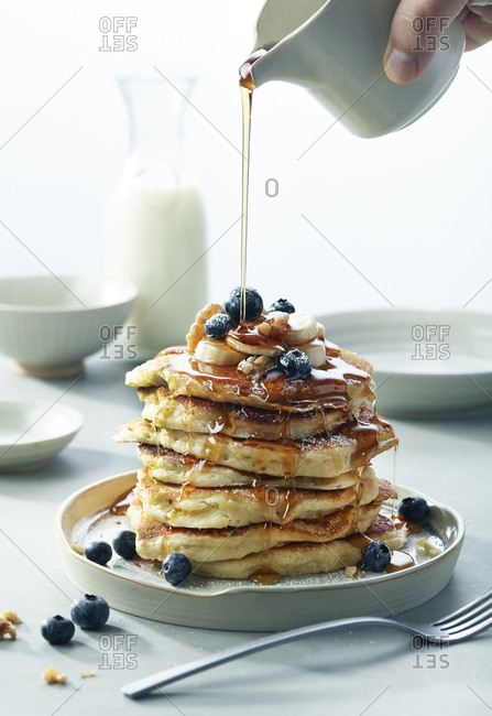 Stack of Blueberry Banana Walnut pancakes with Syrup Pouring Breakfast