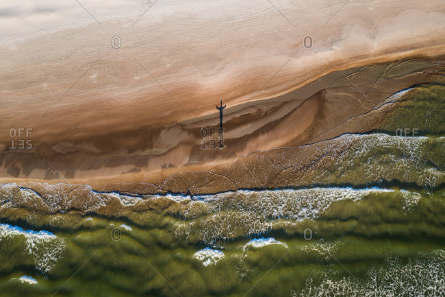 Aerial view of person silhouette shadow standing on Baltic sea shore beach in Klaipeda, Lithuania. Perspective of beautiful nature patterns on surface.