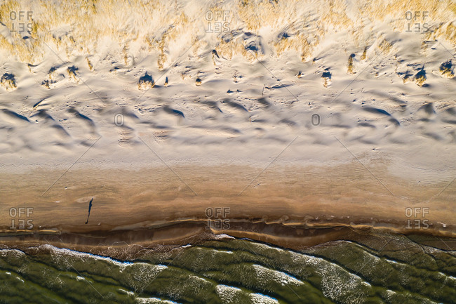 Aerial view of person silhouette shadow standing on Baltic sea shore beach in Klaipeda, Lithuania. Perspective of beautiful nature patterns on surface.
