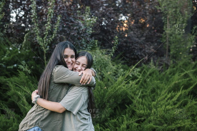 Teenage girls hug happily outside