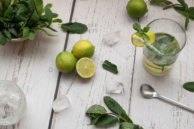 Top view of a mojito cocktail and its ingredients on a white rustic table