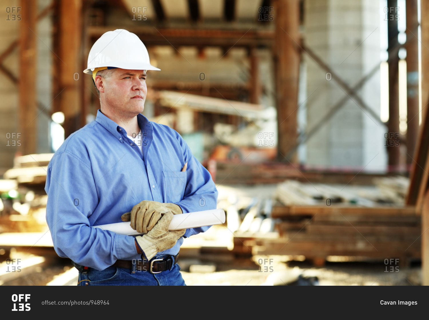 Male construction foreman holding plans looking off camera