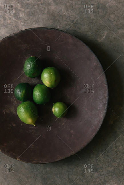 A bunch of fresh limes in a plate at a Mexican restaurant