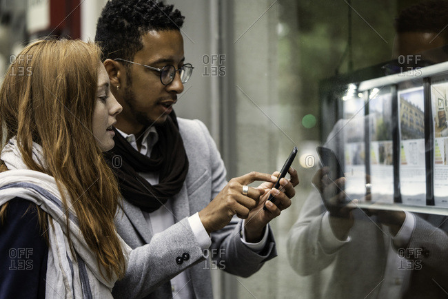 Couple using smartphone at window display