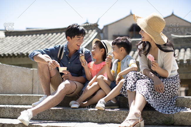 Happy young Chinese family eating ice cream outside