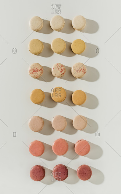 Assortment of macarons arranged in rows on white surface