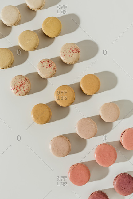Overhead view of an assortment of macarons arranged in rows on white surface