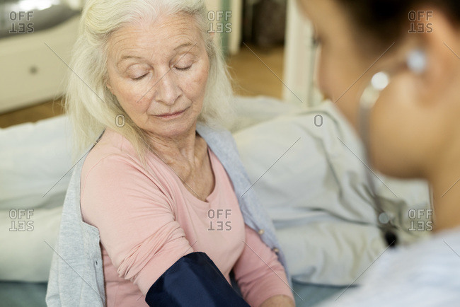 Home caretaker checking blood pressure of senior woman