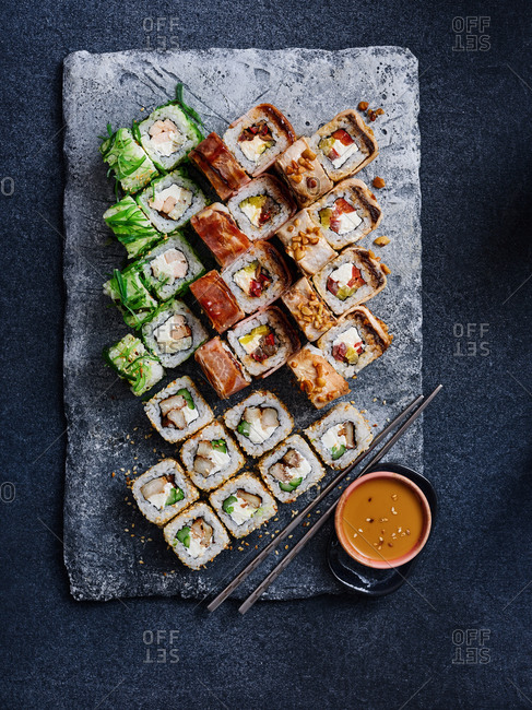 Premium Photo  Tasty sushi rolls set on black plate with sauces