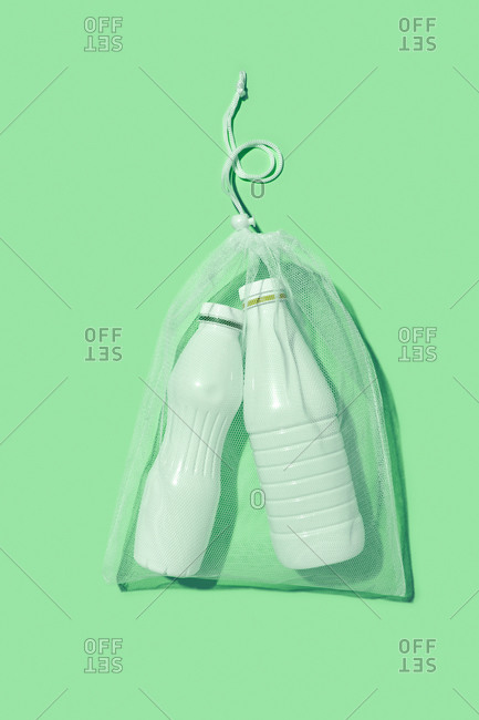Transparent refillable package with two plastic mock-up bottles on a light green background with shadows, copy space. Flat lay. Eco friendly concept.