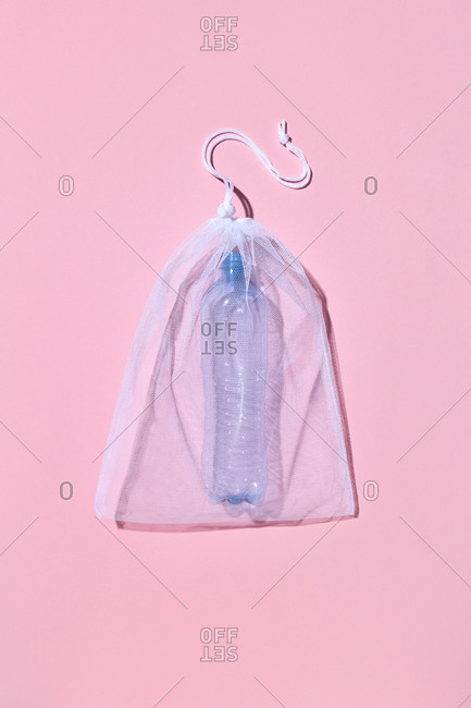 Used empty plastic bottle in a refillable package as a garbage on a light pink background with shadow, copy space. Waste sorting concept.