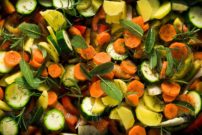 Close up view of various vegetables and aromatic herbs on a baking sheet, ready for baking. Natural healthy vegetarian food.
