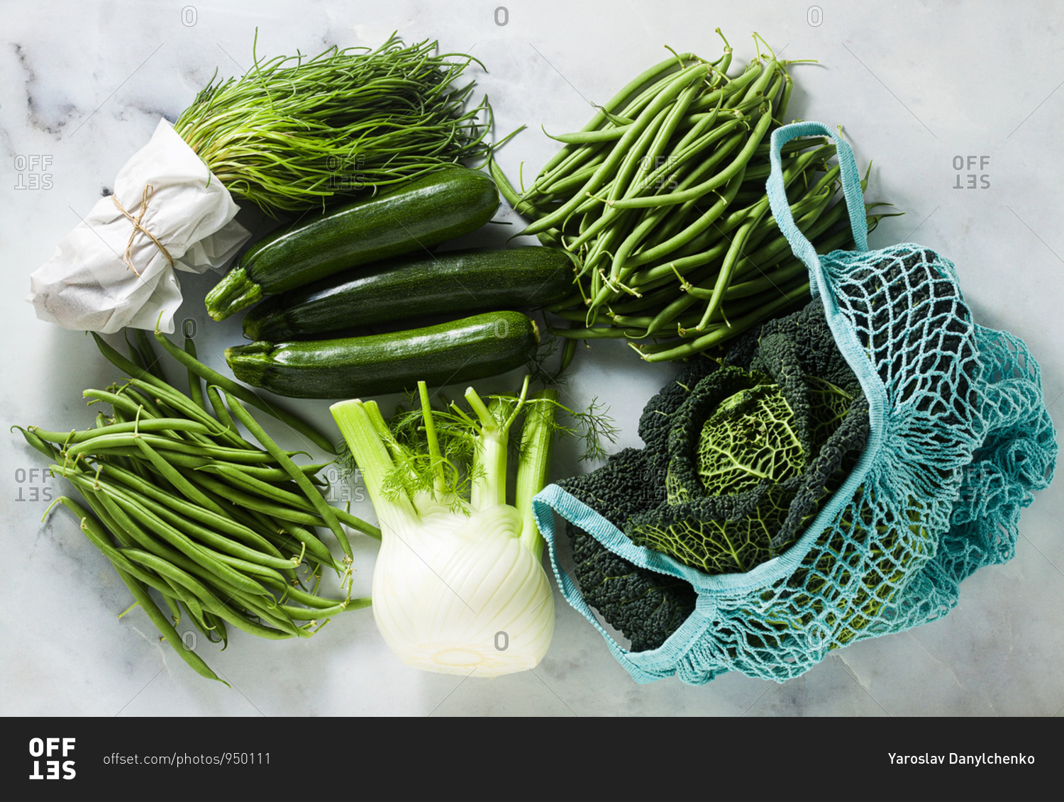 Green Italian vegetables on a marble table and Cotton Mesh Net String Shopping Bag. Zucchini, green beans, fennel, savoy cabbage and Salsola soda.