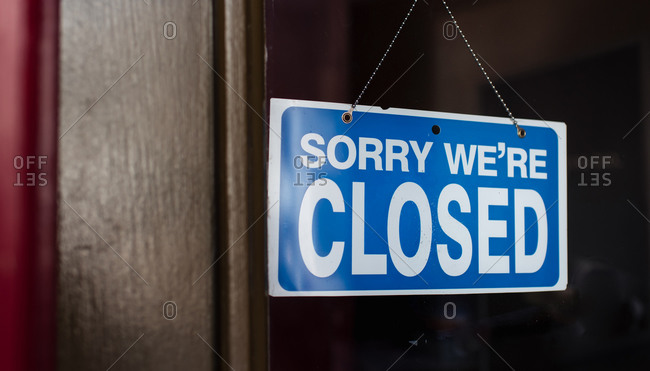 Close up of a closed sign hanging in the window of a store.