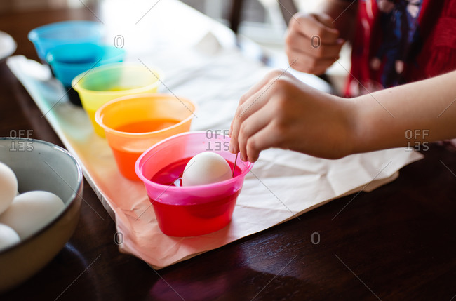 Close up of a child's hand dying an egg for Easter decoration.