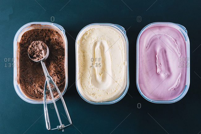 Chocolate, vanilla and strawberry ice cream tubs with scoop