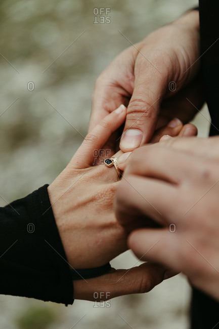 Man puts custom engagement ring on woman's finger after proposal