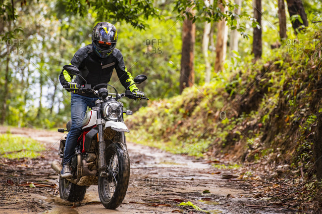 Man riding his scrambler type motorcycle through forest