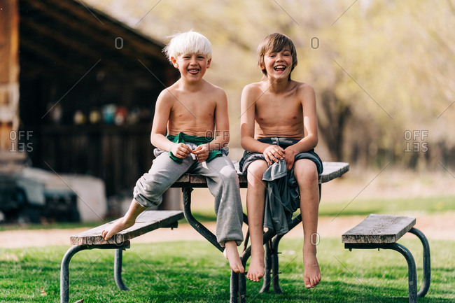 Two children smiling sitting on picnic table
