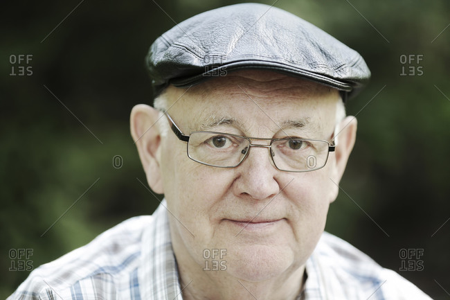 Germany- North Rhine Westphalia- Cologne- Portrait of senior man with cap and glasses in park- smiling