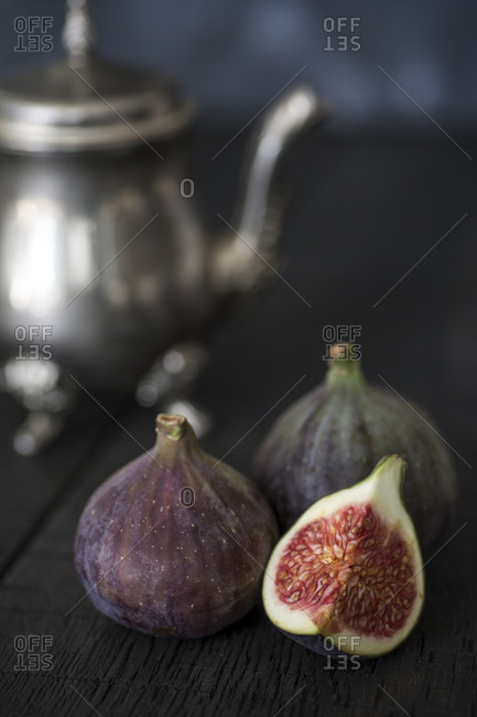 Whole and sliced figs with silver teapot in the background