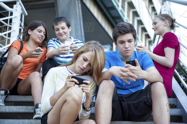 Teenage friends using mobile devices on stairs