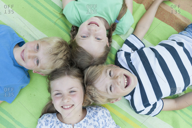 Germany- Bavaria- four smiling children lying on a blanket