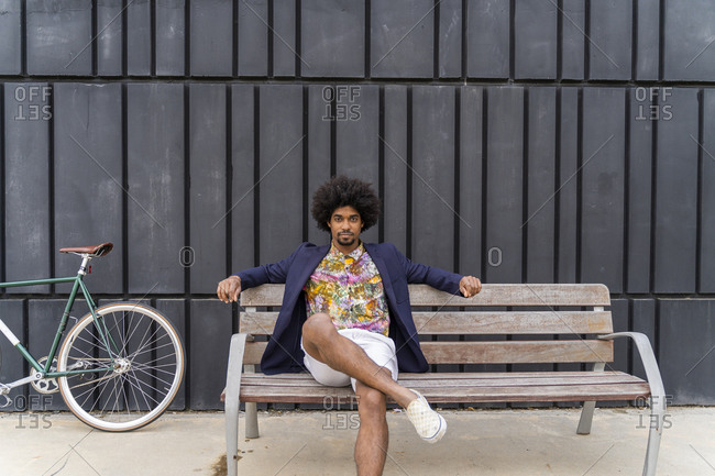 Stylish man with bicycle sitting on a bench