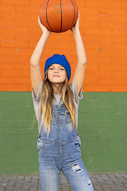 Young girl holding up a basketball outside