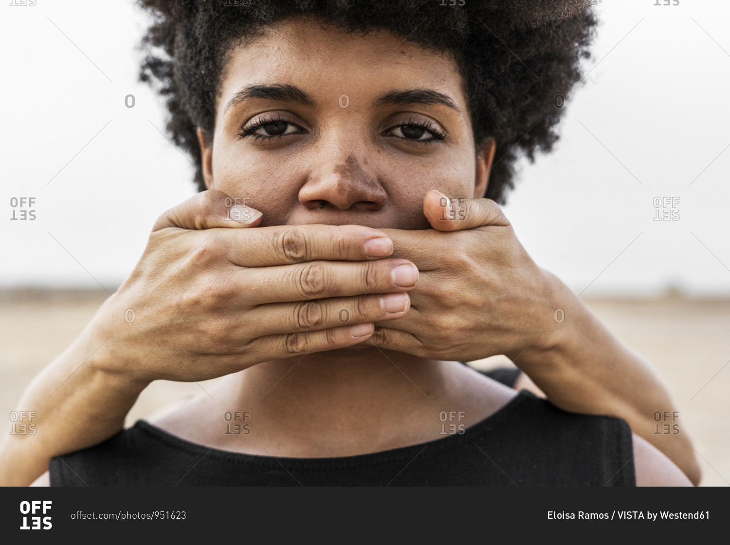 Woman's hands covering mouth of another woman- close-up stock photo - OFFSET