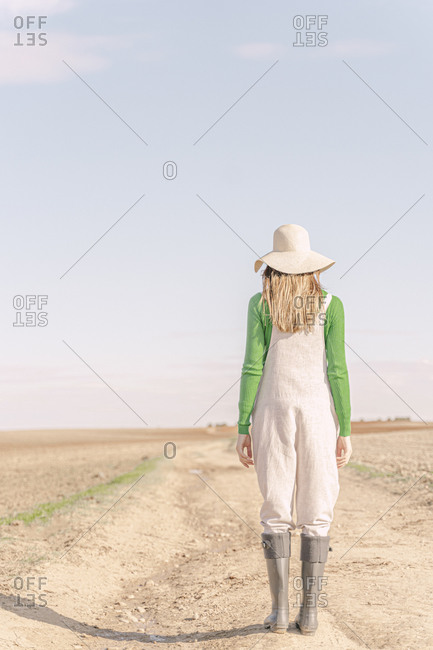 Young woman looking at dry field dry field- rear view