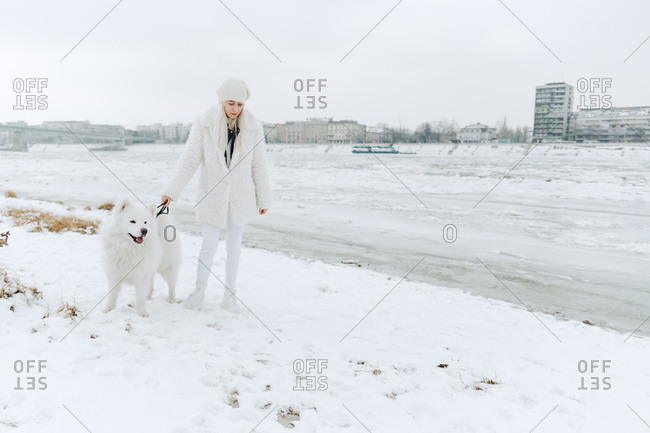 Serbia- Petrovaradin- white dressed young woman with white dog at riverside