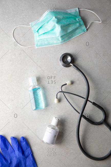 Top view of antibacterial gel for coronavirus prevention placed on table with face mask, thermometer and stethoscope