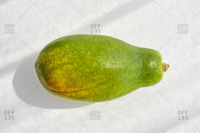 From above whole fresh healthy papaya with seeds placed on white background