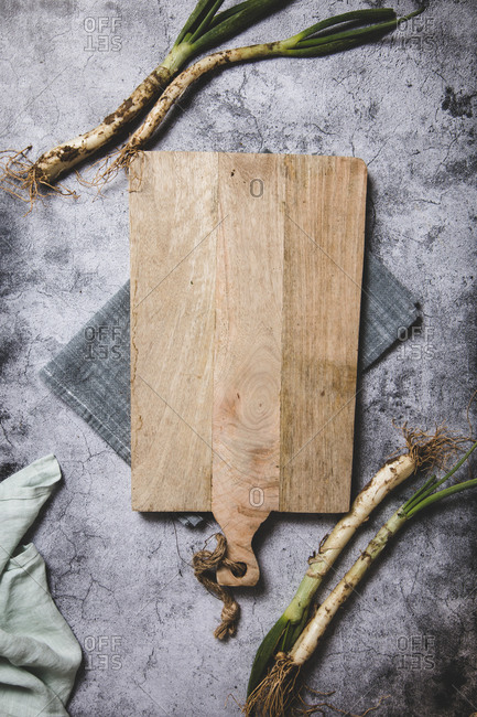 Top view of bunch of ripe dirty calsot onion placed on tray and linen cloth on wooden table near knife in Catalonia, Spain