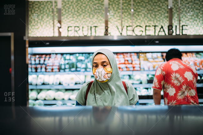 Asian woman shopping in a grocery store wearing a facemask
