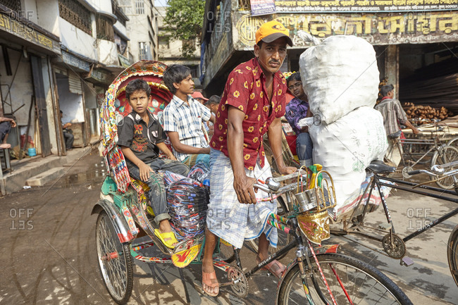 Dhaka, Bangladesh - April 27, 2013: Cycle-rickshaw with passengers on a busy street in Dhaka, Bangladesh