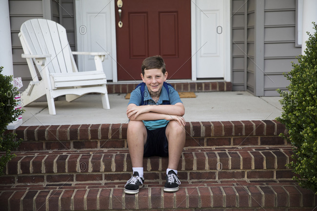 Smiling Tween Boy With Braces Sits on Brick Front Steps
