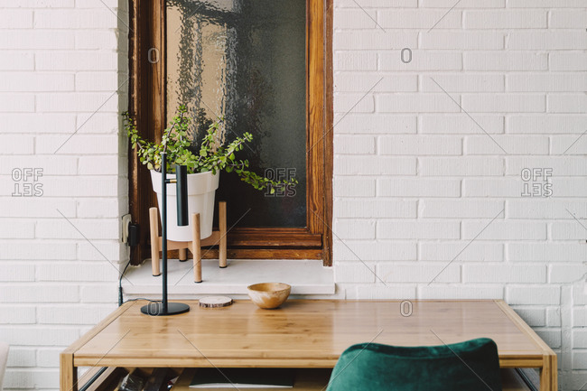 Wooden table and chair against houseplant on windowsill at home office