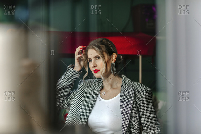 Portrait of beautiful woman with red lipstick looking out of window