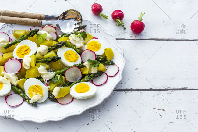 Plate of vegetarian potato salad with boiled eggs- asparagus- radishes and parsley