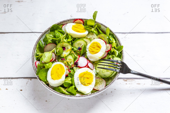Bowl of vegetarian salad with boiled eggs- radishes- cucumbers- corn salad and edible flowers