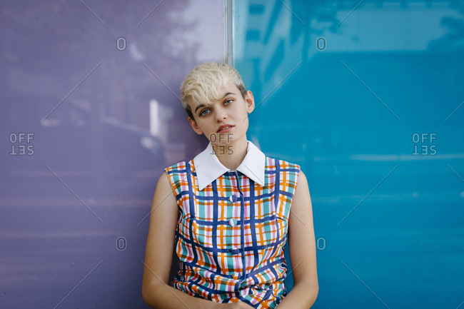 Portrait of female teenager wearing colorful dress leaning on multicolored glass wall