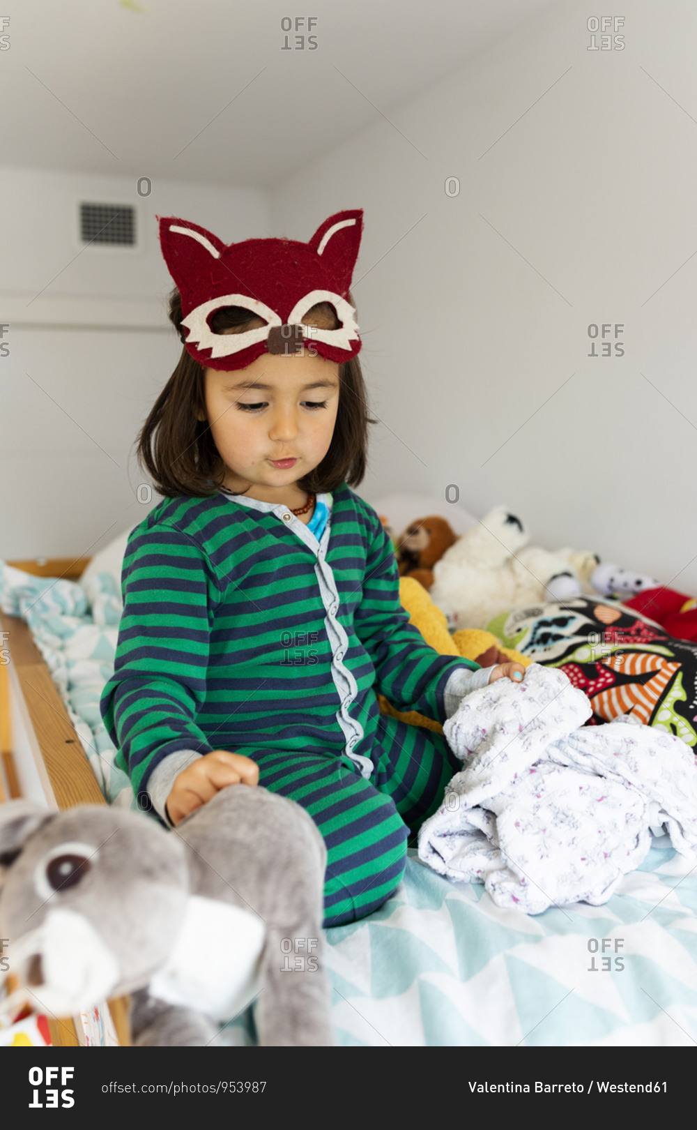 Portrait of little girl with fox mask crouching on bunk bed at home