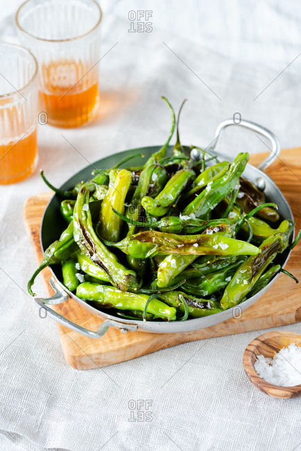Fried shishito peppers (padron peppers) in vintage skillet with glasses of beer
