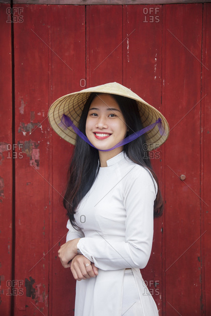 January 10, 2019: A young Vietnamese woman in traditional dress standing at  the Western gateway to the Purple Forbidden City, Hue, Vietnam, Indochina, Southeast  Asia, Asia stock photo - OFFSET
